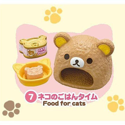 A brown plush toy bear with a yellow ear and nose, sitting next to a can of cat food, and a small yellow bowl with food inside. The image also includes paw prints and text in Japanese.