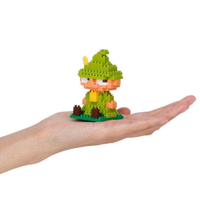 A hand holding a small green and yellow toy figure, resembling a pixelated character or a miniature figurine.