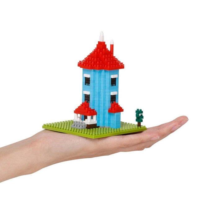 A hand holding a small, colorful, and intricate model of a house made of building blocks.