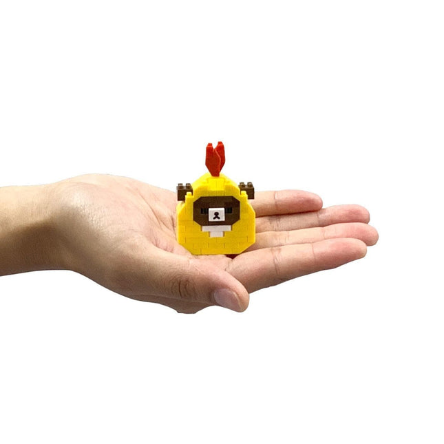 A hand holding a small yellow and red toy with a face on it.