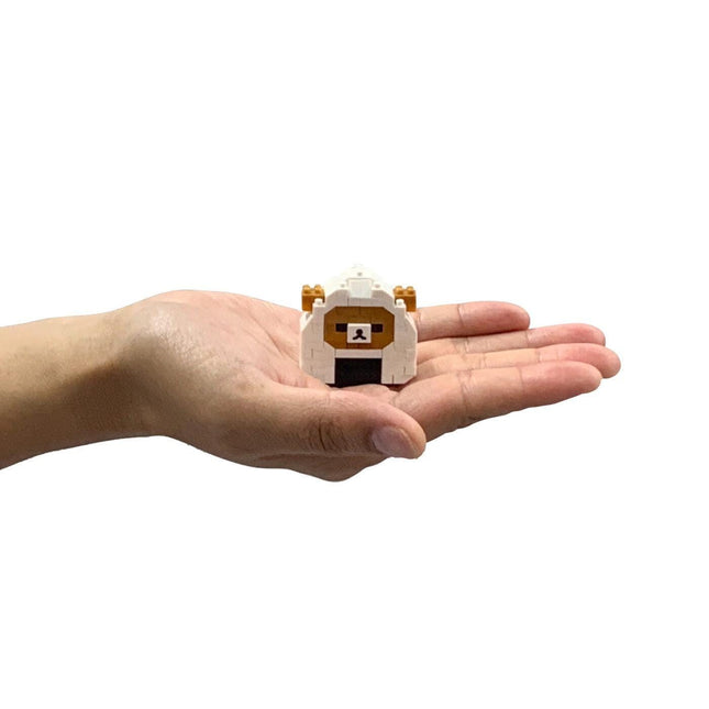 A hand holding a small white and brown toy resembling a sheep or lamb.