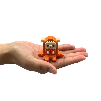 A hand holding a small orange and white toy figure.
