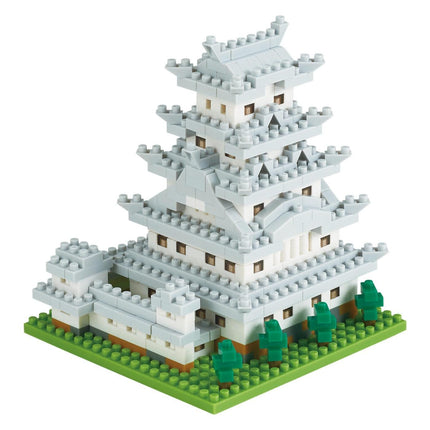 A 3D model of a white castle-like structure made of small white and gray building blocks, set against a green grassy background.