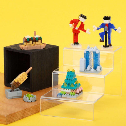 a collection of colorful, small toy figurines and a black wooden box on a wooden surface against a yellow background.