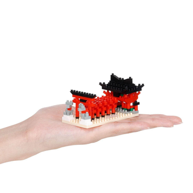 A hand holding a small, colorful, and intricate model of a temple or pagoda-like structure made of small, colorful building blocks.