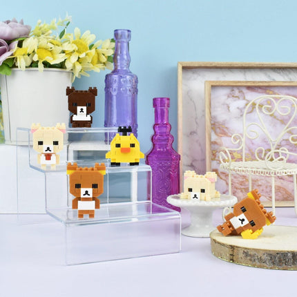 a collection of small, colorful, and whimsical objects, including a miniature bear, a yellow bird, and several other small figures, all displayed on a shelf or table.