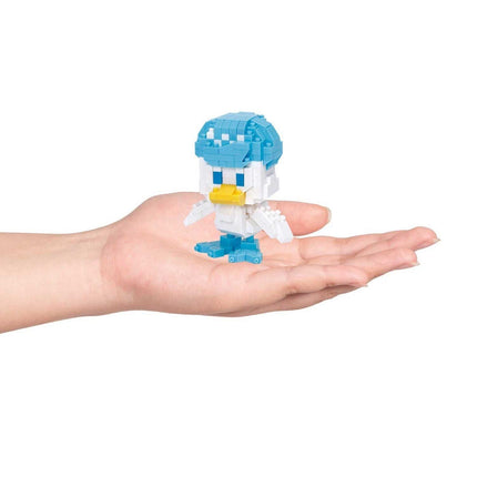 A hand holding a small, colorful, pixelated toy figure of a duck.