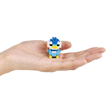 A hand holding a small, colorful, pixelated character resembling a penguin or duck.