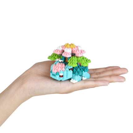 A hand holding a small, colorful, and intricate toy made of small, colorful building blocks.