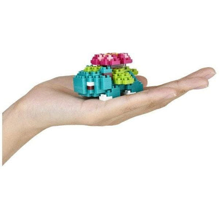 A hand holding a small, colorful, and intricate toy made of small, colorful building blocks.