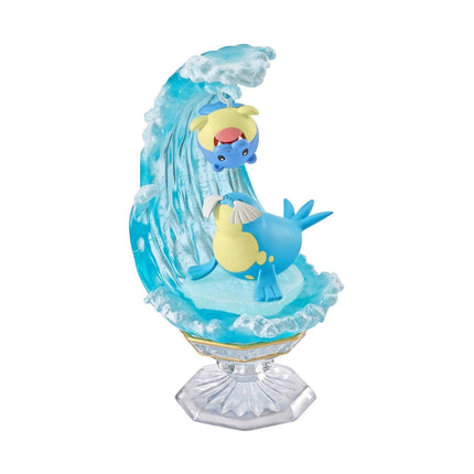 A figurine of a blue and yellow sea creature, possibly a seal or a similar marine animal, sitting on a wave-like structure.