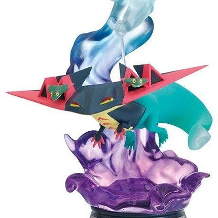 A figurine of a dragon-like creature with a blue and green body, red wings, and a purple base, standing on a platform.