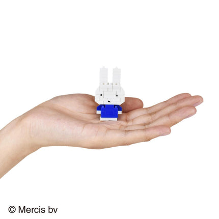 A hand holding a small white and blue toy, which appears to be a small robot or figurine.