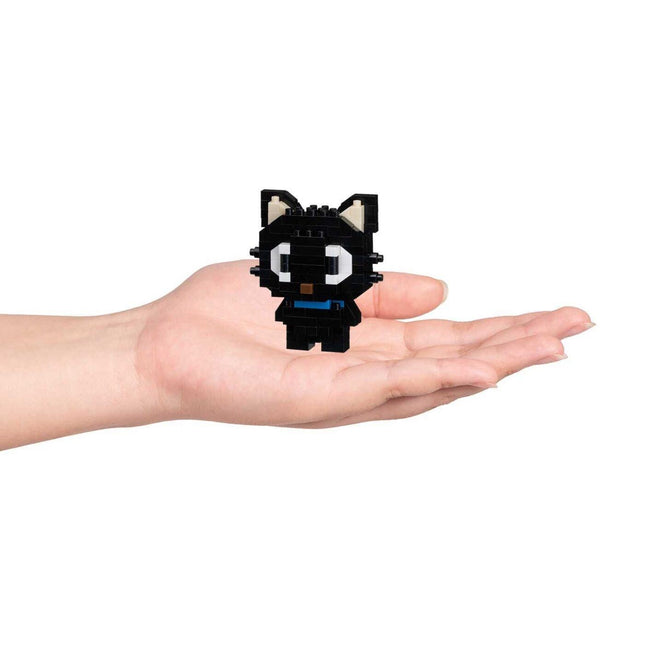 A hand holding a small black cat-shaped object.