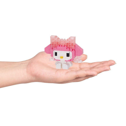 A hand holding a small pink and white toy resembling a character from a children's television show or movie.