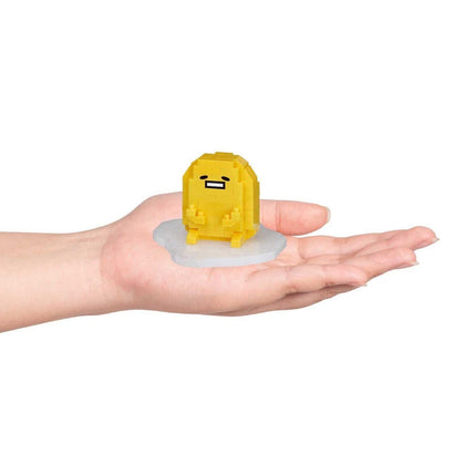 A hand holding a small yellow, pixelated character on a white base.