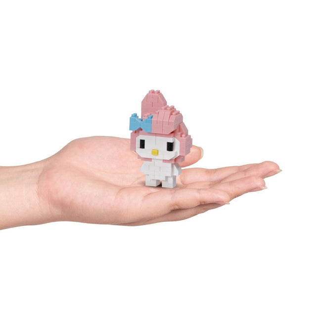 A hand holding a small, pink and white Hello Kitty-style figure.