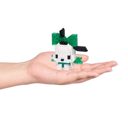 A hand holding a small white and green toy, which appears to be a small toy figure or a miniature version of a character.