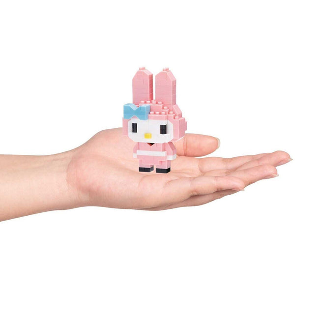 A hand holding a small pink Hello Kitty figurine.