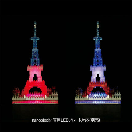 two Eiffel Tower-like structures made of colorful building blocks, illuminated against a dark background.