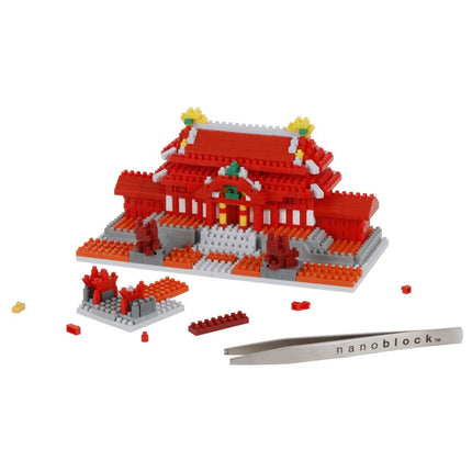 A red and white building made of building blocks, with a pair of tweezers and some additional building blocks on the side.