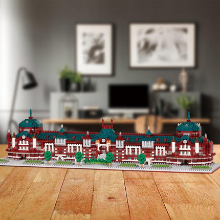 A model of a building made of small red and white bricks, with green roofs and decorative elements, displayed on a wooden table.