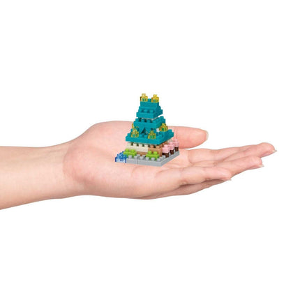 A hand holding a small, colorful, and intricate toy or model, resembling a miniature version of a larger structure or object.