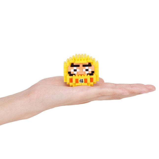 A hand holding a small yellow, pixelated character resembling a face or a character from a video game.