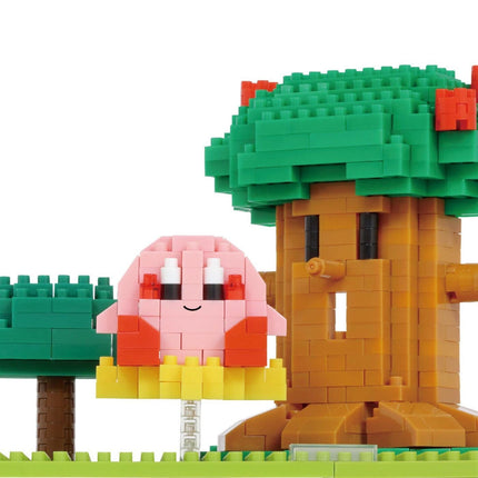 A pink and orange pixelated character resembling a character from a video game, sitting next to a green tree-like structure made of small building blocks.