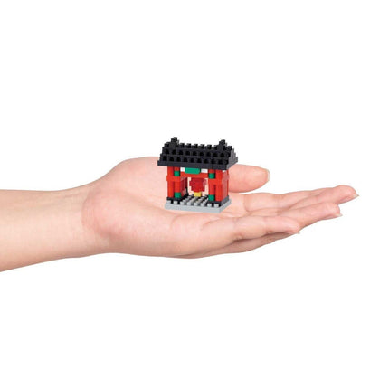 A hand holding a small, colorful, and intricate toy house made of building blocks.