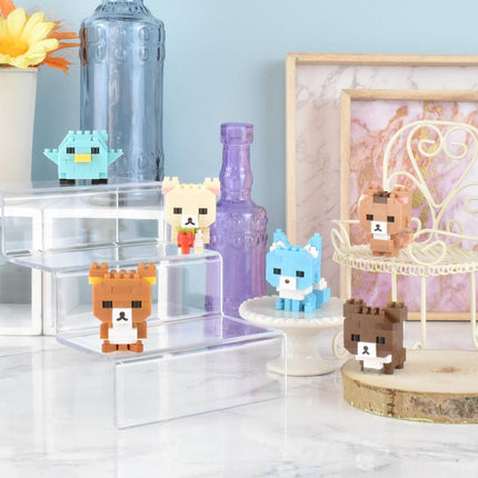 a collection of small, colorful, and whimsical figurines or toys, including a bird, a bear, a cat, and a dog, arranged on a marble surface. There are also some decorative elements such as a vase, a bottle, and a picture frame in the background.