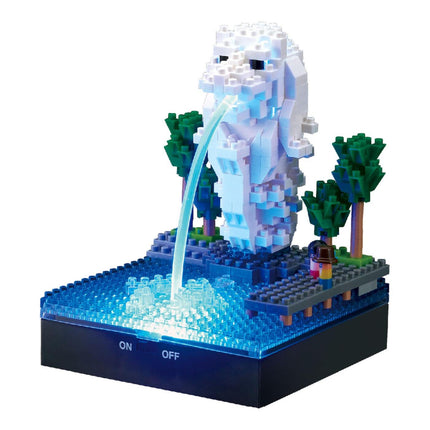 A miniature Lego sculpture depicting a fountain with a water spout, surrounded by trees and other Lego elements.