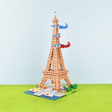 A colorful, three-dimensional model of the Eiffel Tower made of small building blocks, with a miniature landscape and other small objects around it.
