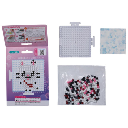 various items related to a craft or art project, including a box with instructions, a clear plastic container, and a bag filled with small, colorful beads or tiles.