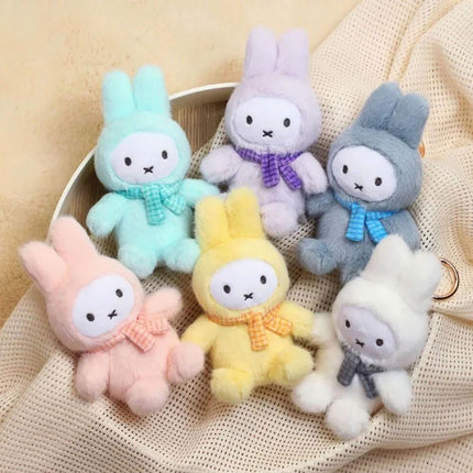 A group of six colorful stuffed bunny toys, each with a unique color and pattern, arranged together on a beige fabric surface.