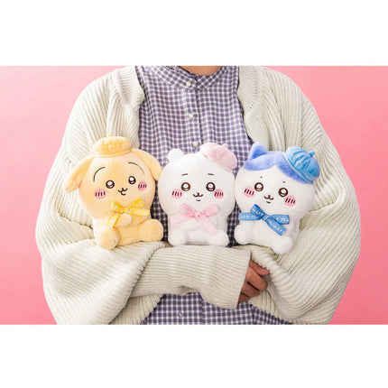 Three sitting plush toys: yellow, white with pink bow, and white with blue scarf