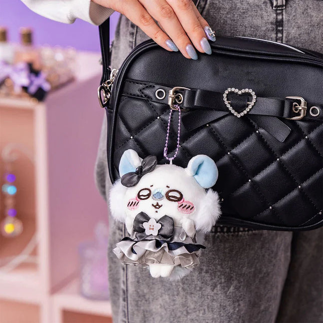 White plush mascot keychain hanging from black quilted crossbody bag