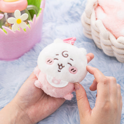 White and pink Chiikawa plush mascot with closed eyes and rosy cheeks, held in hands