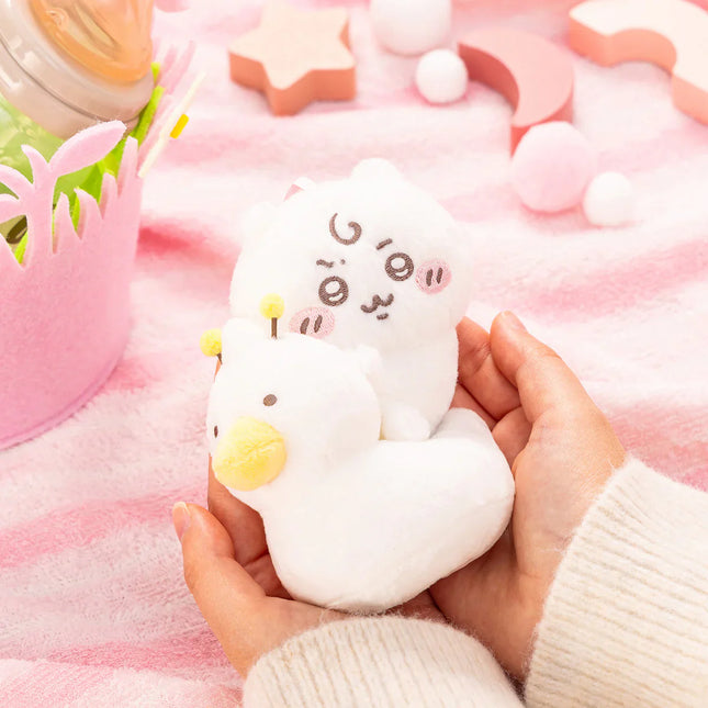 Plush baby potty training mascot with yellow duck-bill, held in hands on pink blanket