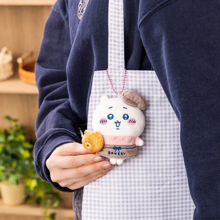 Bakery staff mascot plush keychain held in hand, white character with pink apron