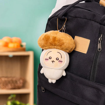 Seasonal plush keychain hanging on a black backpack strap, with tan beret and white face