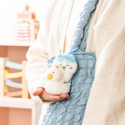 Plush baby potty training mascot with blue hanging strap, held near light fabric