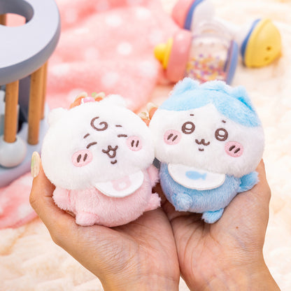 Pair of Chiikawa plush mascots in white and pastel blue/pink, smiling faces in hands