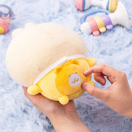 Round yellow plush baby swaddle with sleepy character face on folded swaddle