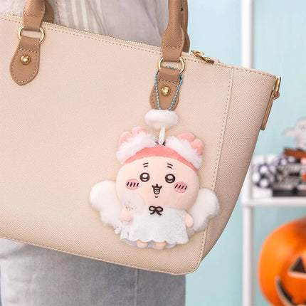 Seasonal plush keychain with pink bunny ears hanging from a beige handbag